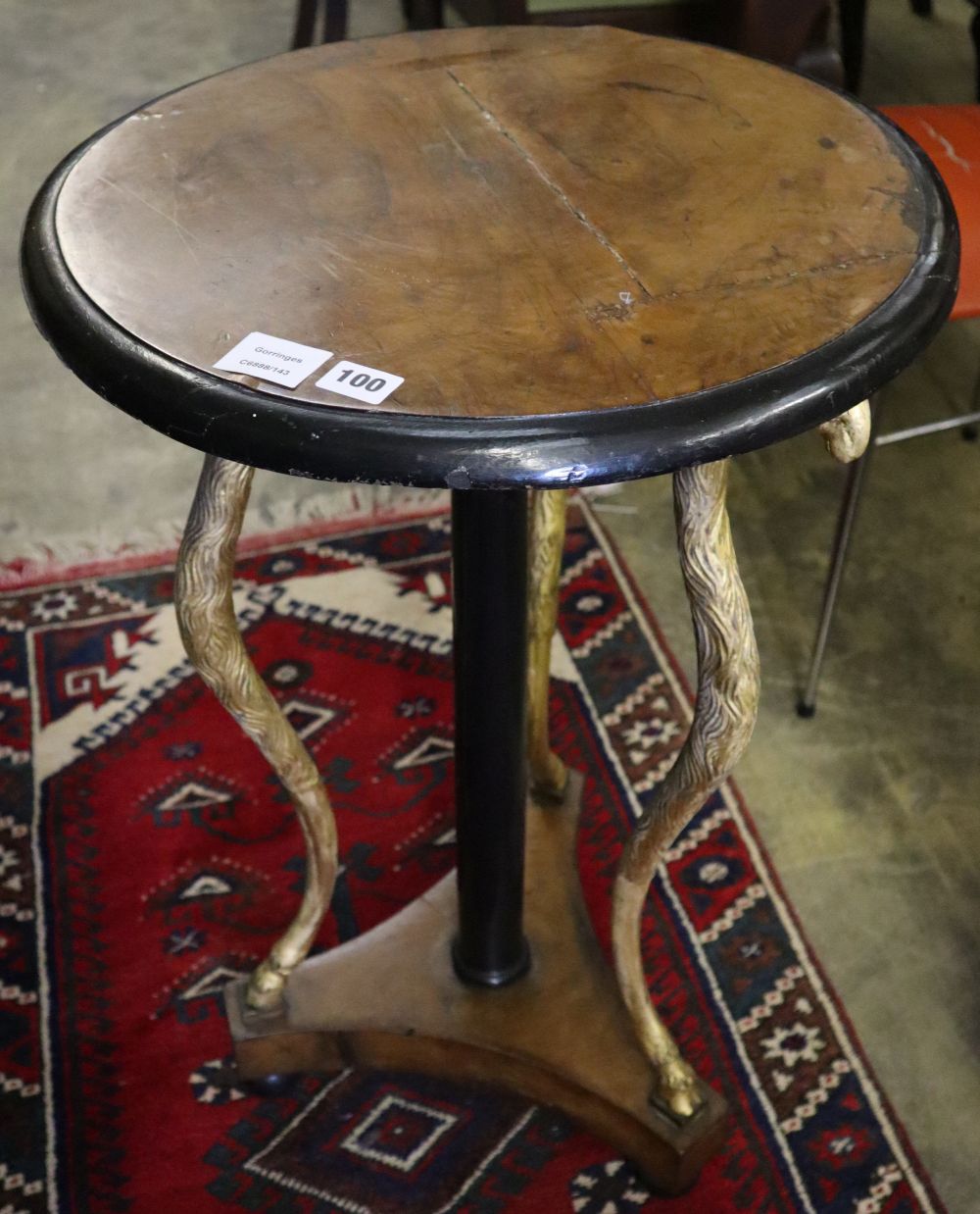 A Regency gilt and ebonised circular walnut occasional table, on triple rams head support, diameter 47cm, height 78cm
